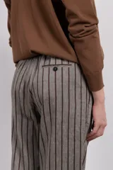 Pantalón de vestir de lino y viscosa color gris con rayas verticales marrones, corte sastrero y pinzas delanteras.