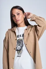 Sobrecamisa color beige de gabardina con cuello camisero, cierre frontal con botones a presión, dos bolsillos de parche en el pecho y corte holgado.