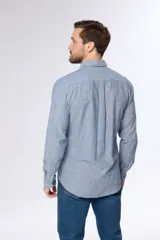 Camisa de lino color beige, de manga larga, con cuello clásico y bolsillo en el pecho.