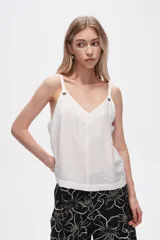 Musculosa blanca de bretel ancho con cuello en V y detalle de ojales metálicos en los tirantes. Corte al cuerpo.