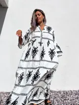 Vestido túnica largo de algodón color blanco con estampado de flores abstractas en negro, escote en V y mangas 3/4 amplias.