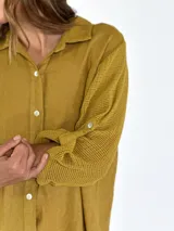 Vestido camisero largo color beige, con cuello clásico, abotonadura frontal completa, mangas 3/4 con trabilla y aberturas laterales.