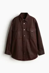 Sobrecamisa marrón de sarga de algodón revestida con cuello, botones adelante y canesú con pliegue de caja en la espalda. Modelo de corte holgado con hombros caídos, mangas largas con puños abotonados y bolsillos superiores con solapa y botón. Bajo redondeado y espalda algo más larga.