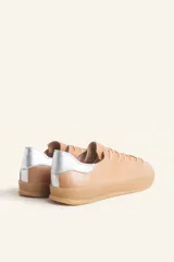 Zapatillas bajas blancas de cuero vacuno con detalle de refuerzo de gamuza color borgoña en el talón y suela de goma color caramelo.