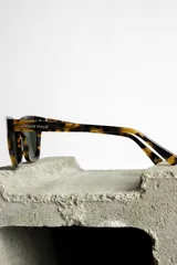 Lentes de sol con montura gruesa color carey y lentes oscuros.