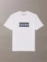Remera blanca de algodón con cuello redondo y manga corta. Presenta un estampado rectangular con rayas horizontales en tonos de gris y azul, y el logo de Calvin Klein en el centro.