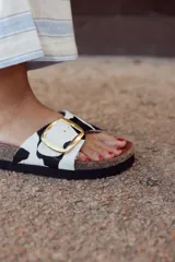 Sandalia abierta con tira de cuero con estampado de vaca y hebilla dorada.