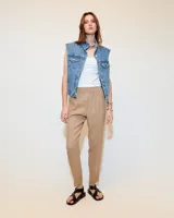 Babucha sastrera color beige confeccionada en tela italiana, de tiro medio y largo hasta los tobillos. Diseñada con cintura elastizada, cartera falsa, bolsillos laterales funcionales y piernas tipo pitillo con raya de aplomo.