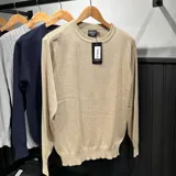Buzo de hilo color beige, marca Ganbaru, con cuello redondo y mangas largas.