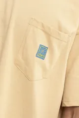 Remera color celeste con bolsillo en el pecho y logo estampado en color naranja.