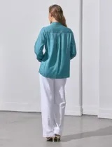 Camisa blanca de lyocell, marca Dash. Tiene cuello con solapa, abertura central con botones, mangas largas regulables con presilla y botón, y dos bolsillos delanteros aplicados.