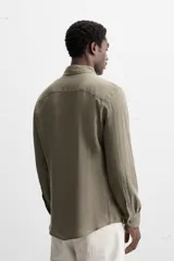 Camisa celeste de lino, de corte recto, manga larga y cuello clásico.