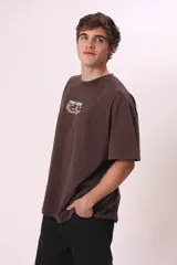 Camiseta de manga corta, color gris oscuro con efecto lavado, corte oversize y cuello redondo. Presenta texto estampado en blanco en el pecho que dice "CREW MEMBER".