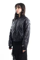 Campera bomber negra de tela satinada con cierre frontal, cuello redondo y puños y cintura elastizados. Tiene un pequeño logo bordado en el pecho y un bolsillo con cierre en la manga. Es reversible.