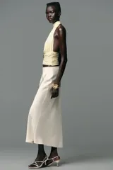 Top color crema con cuello halter, espalda descubierta, detalle de frunces y pieza metálica en forma de sol en el delantero.