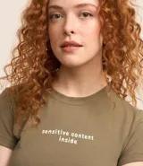 Blusa corta color verde militar, de rib de algodón, con cuello redondo, mangas cortas y estampado frontal con la frase "sensitive content inside".