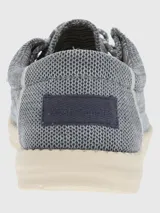 Alpargata negra con cordones elásticos y suela blanca con textura.
