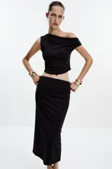 Falda midi color crema, de tiro alto con cintura elástica y detalle de pliegues laterales.