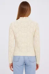 Sweater color crudo con cuello alto con volados y tejido calado.