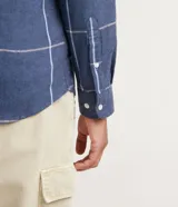 Camisa de franela azul con estampado de cuadros blancos y beige, de manga larga y cuello camisero.