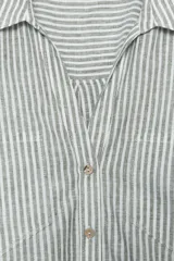 Camisa a rayas verticales grises y blancas, confeccionada en hilatura con lino, de cuello solapa y escote pico. Manga corta con trabilla y botón. Bajo asimétrico. Cierre frontal con botón.
