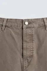 Pantalón de jean color marrón topo, de corte holgado y amplio en toda la pierna, con tiro medio, cinco bolsillos, efecto lavado, detalle de pinzas en perneras y cierre frontal con cremallera y botón.