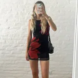 Vestido corto negro con estampado de flores rojas, confeccionado en microtul forrado.