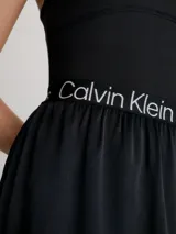 Vestido corto negro de Calvin Klein Jeans con corte evasé, breteles anchos y espalda deportiva. Presenta una banda elástica con el logo de la marca en la cintura.
