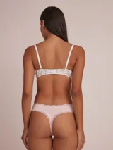 Colaless blanca de algodón con detalle de puntilla en la cintura y moño decorativo.