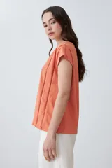 Remera color durazno con escote en V y detalle de vainillas en los laterales. De manga corta y corte recto.