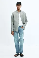 Camisa de lino color gris con cuello inglés, tapeta clásica, canesú en la espalda, mangas largas con tapeta de manga y botón, cierre ajustable de botón en los puños y bajo redondeado.
