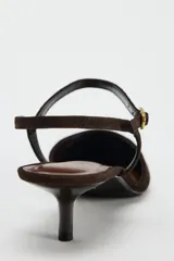 Zapato destalonado de ante color marrón oscuro, con tacón kitten y punta fina. Cierre mediante hebilla en la pulsera al tobillo.
