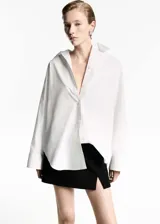 Camisa oversize blanca de popelina de algodón, con cuello camisero, manga larga con puños abotonados y cierre frontal con botones.