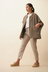 Chaleco color crema de lana sin teñir, corte recto, con cuello y solapa pronunciadas, broches a presión y bolsillos ojal.