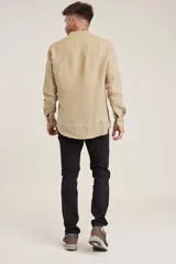 Camisa de lino color beige claro, de corte slim, con cuello mao y mangas largas.