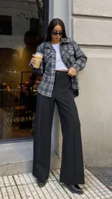 Pantalón de vestir negro de corte palazzo, con cintura alta, bolsillos laterales y cierre frontal con botón.