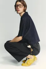 Zapatillas deportivas amarillas con detalles en negro y blanco. Presentan una combinación de materiales y texturas en el cuerpo, tirador en la lengüeta y cierre mediante cordones.