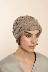 Gorro tejido a mano color crudo, con hilado rueca y variedad de texturas: punto garbanzo y guarda con diseño de trenzas.