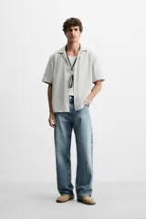 Camisa de manga corta con cuello bowling y corte relaxed fit, confeccionada en tejido con algodón y diseño a rayas verticales en tonos beige y blanco.