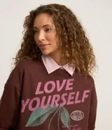 Buzo marrón de algodón con forro de polar, corte oversize, cuello redondo y mangas largas. Estampa frontal con la frase "Love Yourself" en color rosa y dibujo de cerezas.