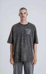Remera negra con efecto nevado, de corte oversize y manga corta. Estampa circular en el pecho con la frase "Tarot Luxo El Mundo" y un dibujo del planeta Tierra.