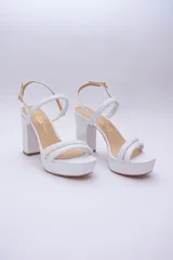 Sandalias blancas de cuero con plataforma y taco alto cuadrado. Tienen dos tiras anchas sobre el empeine y pulsera con hebilla al tobillo.