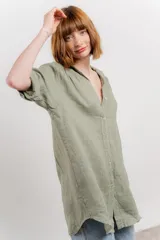 Camisa amarilla de lino con corte recto y calce suelto. Tiene cuello camisero, botones en el frente y mangas cortas con presilla y botón.
