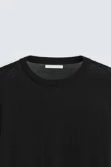 Jersey negro de lana con acabado mercerizado, corte relaxed fit, cuello redondo y mangas largas con terminaciones en rib.