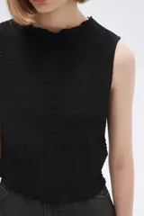 Musculosa negra con textura arrugada, cuello redondo y corte ajustado.