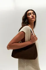 Cartera de hombro marrón de gamuza con asa corta.