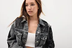 Campera de jean gris oscuro con efecto lavado y apliques de lentejuelas negras en hombros, mangas y bolsillos.