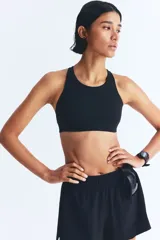 Top deportivo negro de tejido funcional con tecnología ShapeMove™ y DryMove™. Ofrece ajuste ceñido y soporte óptimo. Copas forradas con relleno extraíble, breteles anchos ajustables, espalda nadadora en malla con sección cut-out y cierre de corchetes atrás.