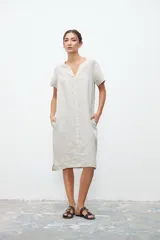 Vestido midi color crudo de lino, corte recto, con cuello en V, mangas cortas y bolsillos laterales.