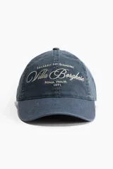Gorra de béisbol azul con efecto lavado, con bordado frontal de la frase "Palazzo Dei Giardini, Villa Borghese, Roma, Italia, 1971" en color blanco.